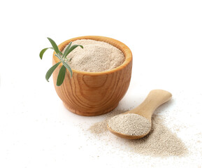 Dry yeast in a wooden cup with a spoon on a white background