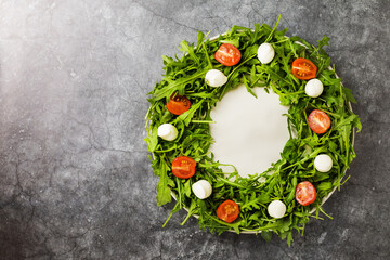 Christmas Wreath Salad: arugula, mozzarella and cherry tomatoes on black plate