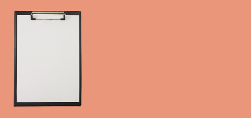 Black clipboard with blank white sheet attached on orange background. Banner. Copy space.