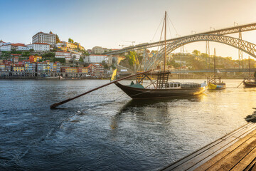 Porto, Portugal. Sunrise view of trditional boats rabelo with Dom Luis bridge on Douro river with old town of Oporto city