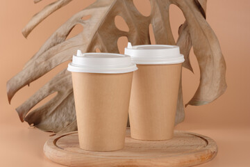 Cardboard cups for hot drinks, tea or coffee on a wooden podium or tray. Mockup with copy space. In...