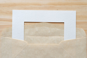 part of a paper frame inside an parchment like paper envelope on a wooden surface