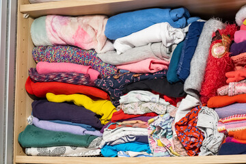 Children's clothes drawer detail, closeup, detail, lots of children's clothes stored in the closet, wardrobe, nobody. Folded clothing piles, unused clothes storage abstract concept, domestic scene