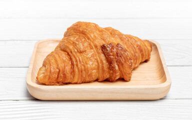 Croissant in wooden plate on vintage white wooden background