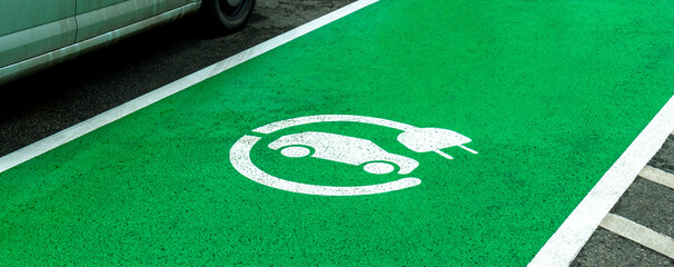 Empty electric vehicle charge station parking spot, marked green zone, car charging device symbol...