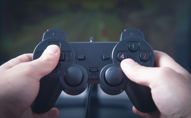 Hands using joystick. Playing video game on computer monitor