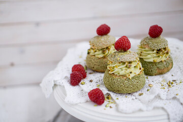 Choux with pistachio cream and raspberry french dessert on white background close up selective focus