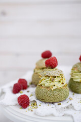 Choux with pistachio cream and raspberry french dessert on white background close up selective focus