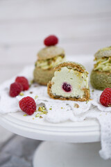 Choux with pistachio cream and raspberry french dessert on white background close up selective focus