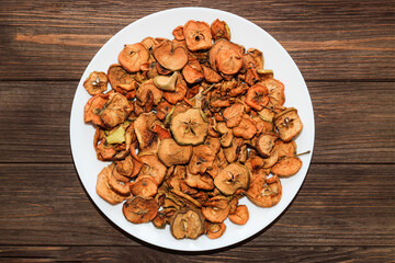 Dried apple fruits on a plate on a wooden table.