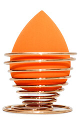 Cosmetic sponge sponge for applying makeup on a golden stand isolated on a white background.