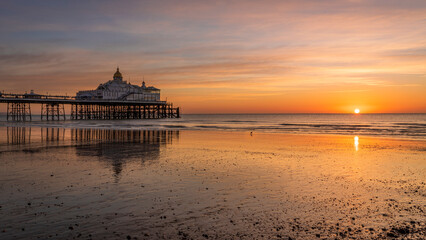 Colourful February sunrise at low tide Eastbourne Pier East Sussex south east England