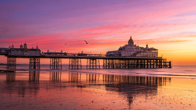 Colourful February sunrise at low tide Eastbourne Pier East Sussex south east England