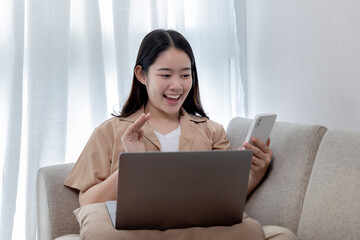 Asian woman talking on the phone and working on a laptop with a smiling face, Business Cell Phone Conversations, Working at home, Home lifestyle, Stay home, New normal, learning, Social distancing.