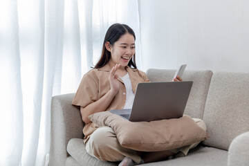 Asian woman talking on the phone and working on a laptop with a smiling face, Business Cell Phone Conversations, Working at home, Home lifestyle, Stay home, New normal, learning, Social distancing.