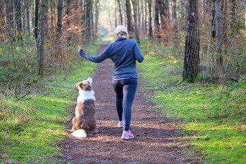 Sportive woman training her dog to sit