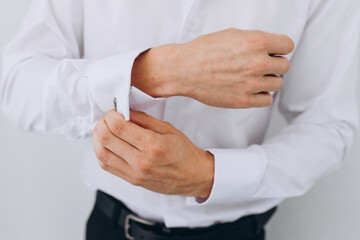 Obraz premium elegant young fashion man looking at his cufflinks while fixing them.