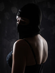 Portrait of a girl in a black balaclava and a black bra.