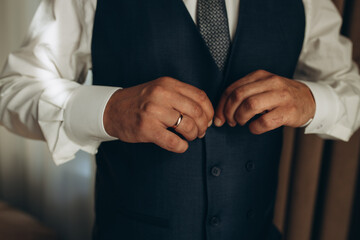 elegant young fashion man looking at his cufflinks while fixing them.