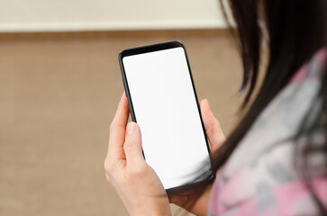 Phone with a blank white display in female hands. Female hands holding smartphone mock-up