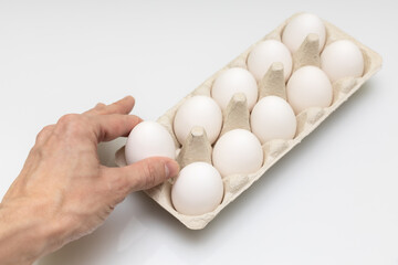 a man's hand takes out a white egg from a cell