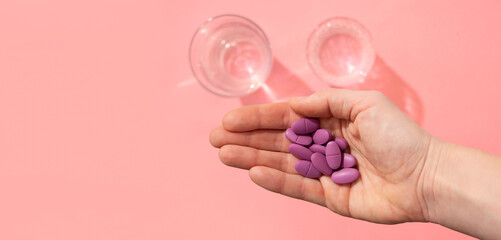 handful of tablets in the palm of your hand next to a glass of water