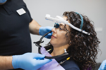 Doctor orthodontist installs a system for diagnosing jaw joints and occlusion for a woman patient