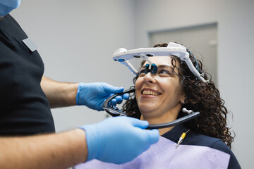 Doctor orthodontist installs a system for diagnosing jaw joints and occlusion for a woman patient....
