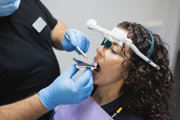 Doctor orthodontist installs a system for diagnosing jaw joints and occlusion for a woman patient