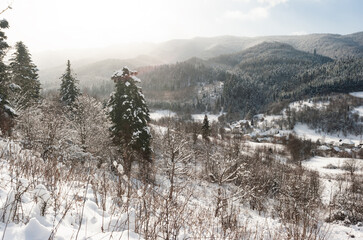 At sunrise, the morning mist looms over the snow-capped mountain forest.