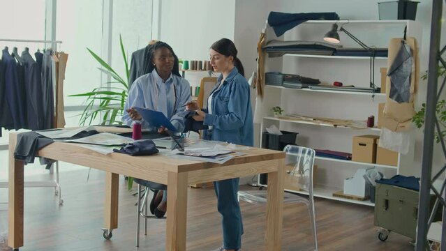 Successful Fashion Designers, a Caucasian Woman and an African-American Woman, Create a New Fashion Collection, Work With Sketches, Fabrics in the Studio. Handicraft, Sewing Business, Fashion Concept.