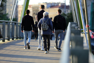 Stara kobieta idzie przez most we Wrocławiu.