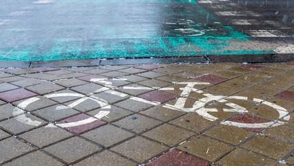 Concept traffic sign. White bike lane sign on wet sidewalk. Bicycle markings.