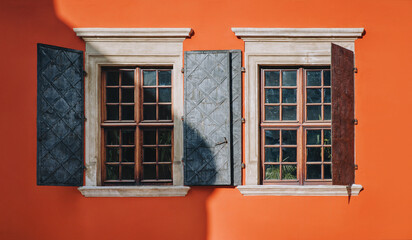 Open metal shutters on the old vintage beautiful windows. Orange facade of the building of the Armenian courtyard in Lviv.