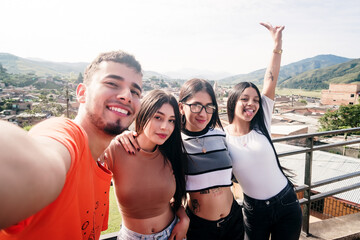 Group of friends taking a selfie from a lookout point in a Colombian village - obrazy, fototapety, plakaty