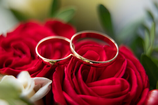 Wedding rings and a bride's bouquet of red and white roses.
