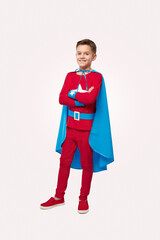 Smiling superhero boy in costume in studio