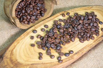 on the burlap-covered table. roasted coffee grains on wooden plate