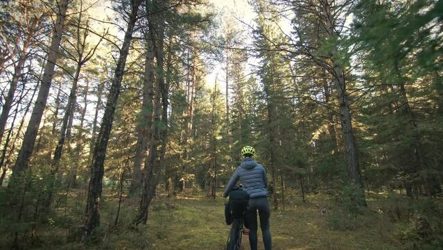 The woman travel on mixed terrain cycle touring with bike bikepacking. The traveler journey with bicycle bags. Magic forest park.