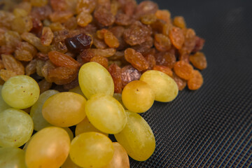 Dried pitted raisins and fresh green grapes stacked together