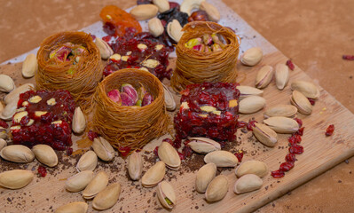 Pistachios, dried fruits, baklava, Turkish delight laid out on a wooden board on a brown background. Oriental sweets