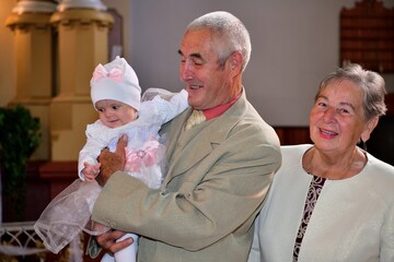 Portrait of old parent with granddaughter during baptism in church
