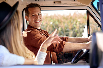 excited caucasian man and woman couple drives an old vintage camper van on road. Family travel...