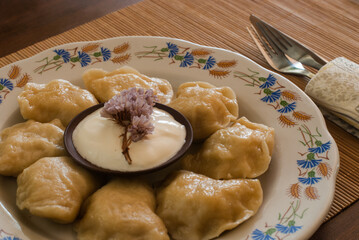 Pierogi. Traditiona Polish food placed on a rustic porcelain wit sour cream.