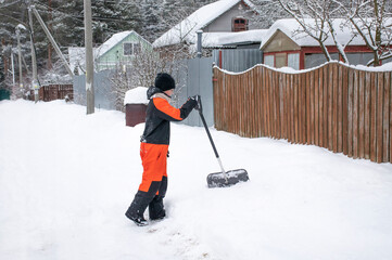 teen boy clearing snow with a shovel on the road in the village