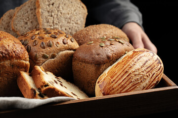 Man holding wooden tray of assorted variety of pastry buns