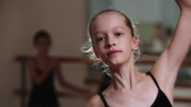 Little girl ballerina with elongated face walks with ballet moves to the camera
