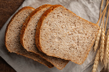 Fresh baked sliced loaf of rye bread on a brown background