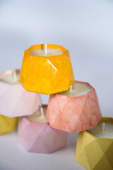 a tower of soy candles in handmade plaster candlesticks in yellow and pink colors