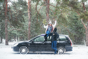 Man and woman traveling by car in winter forest